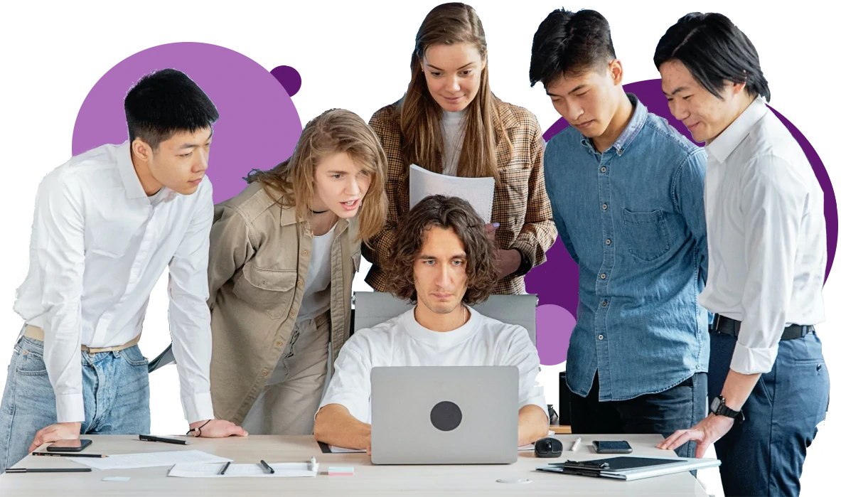 A group of people standing around a man on top of a laptop.